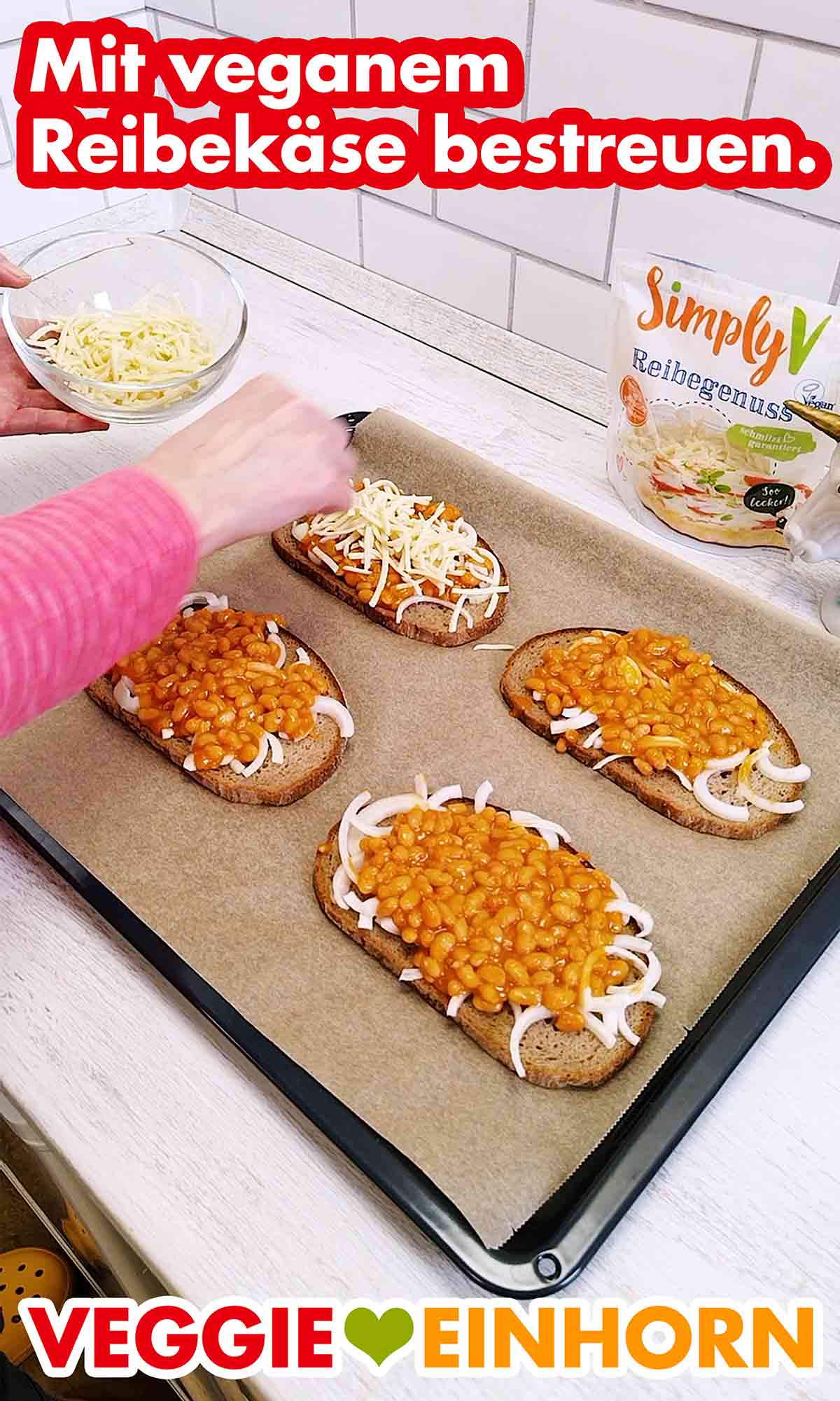 Simply V Reibegenuss wird auf den Baked Beans Broten verteilt. Die Brotscheiben mit Zwiebeln und Baked Beans werden mit veganem Reibekäse bestreut.