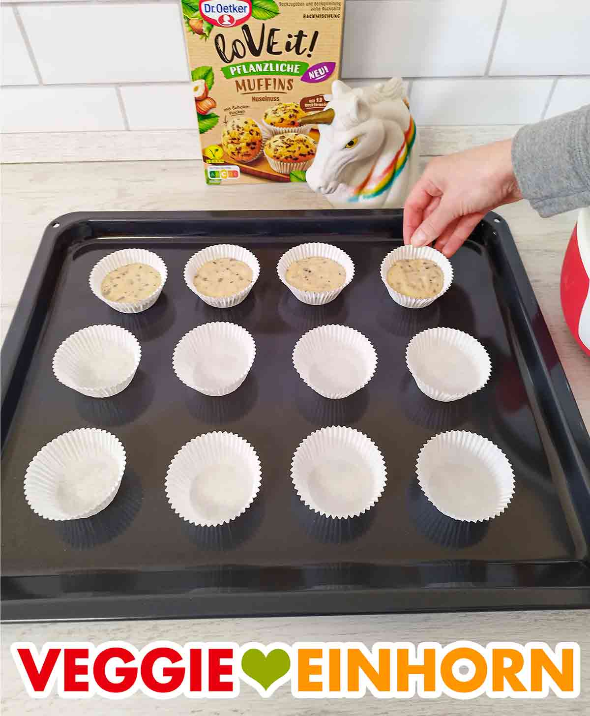 Papier-Muffinformen mit Teig auf dem Backblech Die gefüllten Muffinförmchen auf dem Backblech
