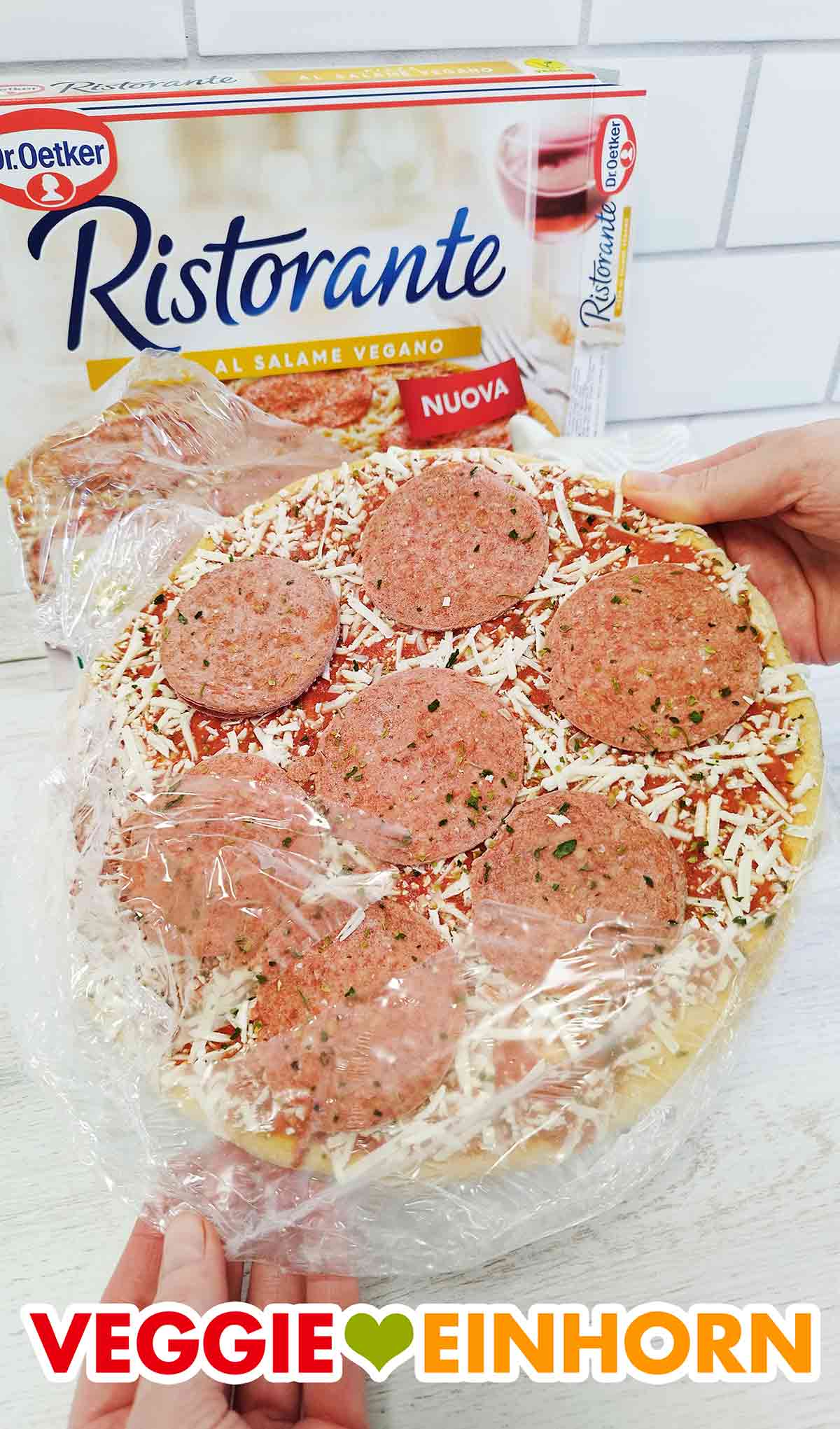 Ich entferne die Folie von der TK Pizza. Entfernen der Folie von der tiefgekühlten veganen Salami Pizza
