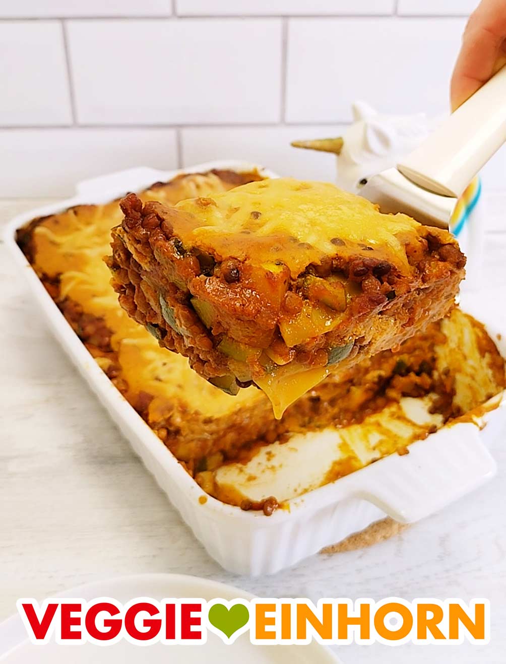 Die vegane Linsen Lasagne wird serviert. Ein Stück vegane Linsenlasagne mit Zucchini auf einem Lasagneheber