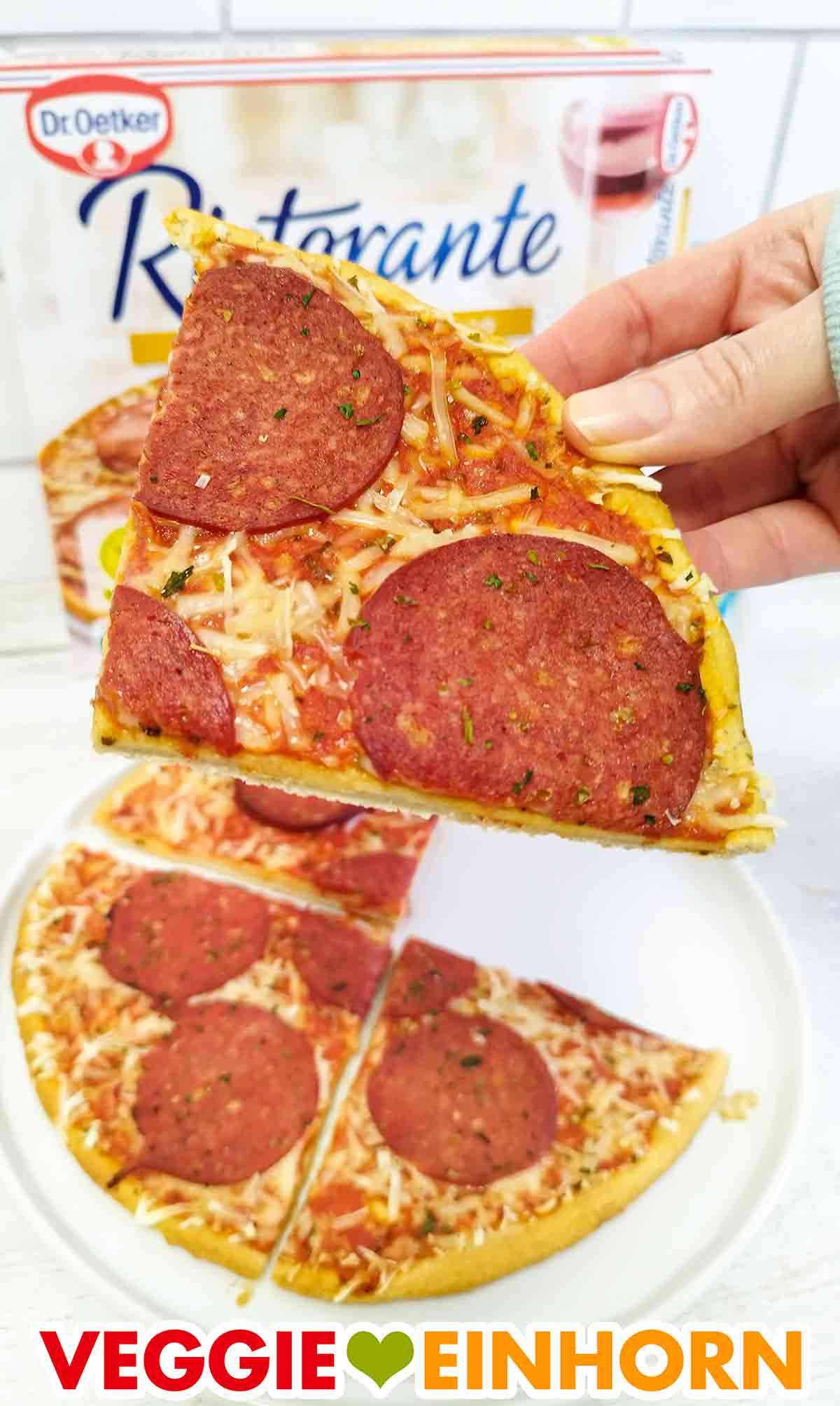 Ein Stück Pizza von Dr. Oetker mit veganer Salami und veganem Käse Eine Hand hält ein Stück vegane Salami Pizza Ristorante