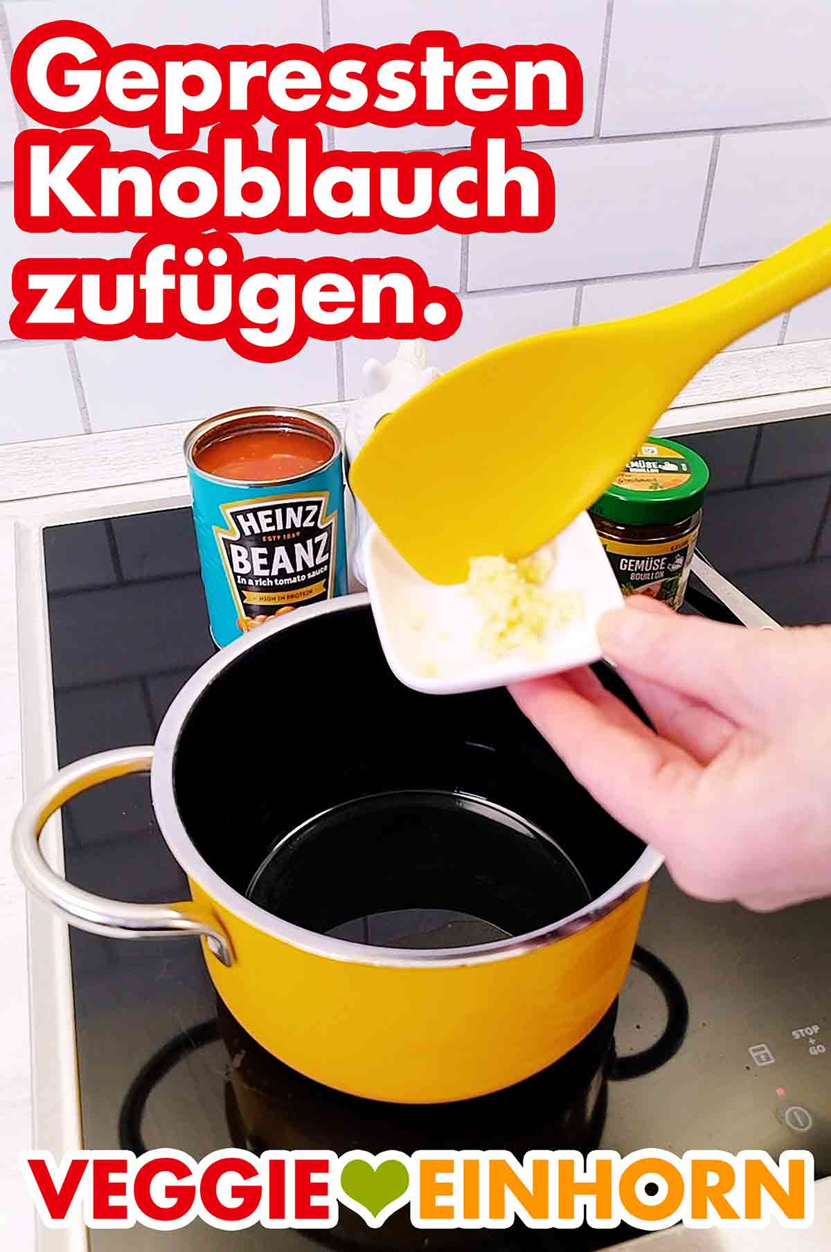 Den Knoblauch in das Bratöl im Topf geben. Der gepresste Knoblauch wird in den Topf mit dem Öl gegeben.