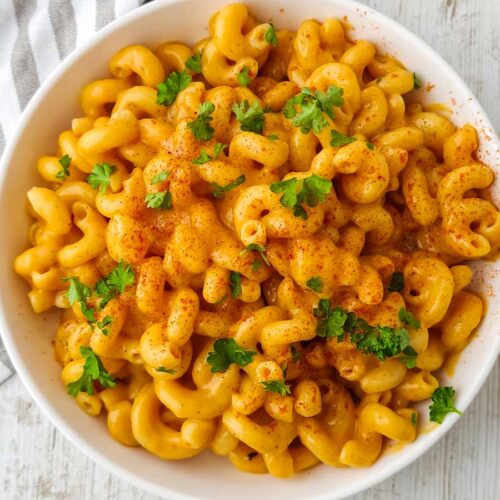 Mac and Cheese mit veganem Cheddar in einem weißen Teller auf hellem Untergrund.