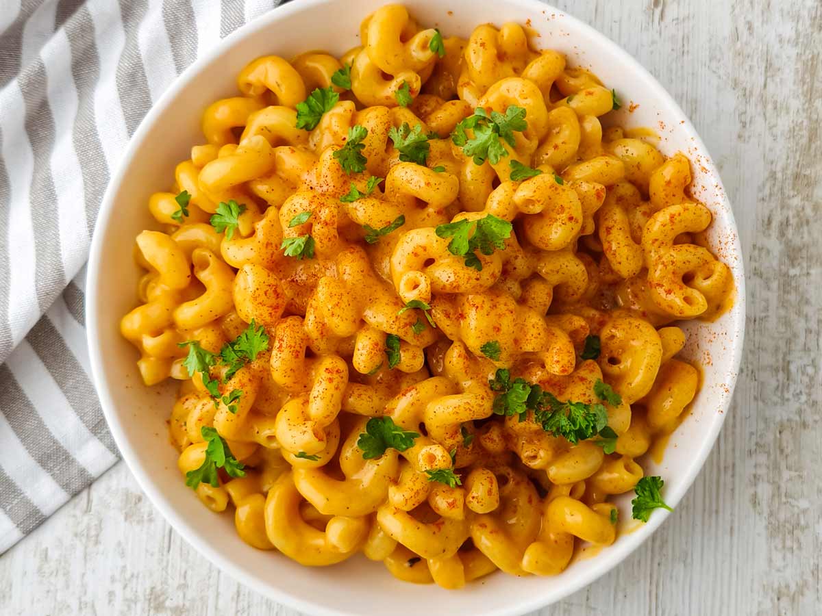 Mac and Cheese mit veganem Cheddar in einem weißen Teller auf hellem Untergrund.