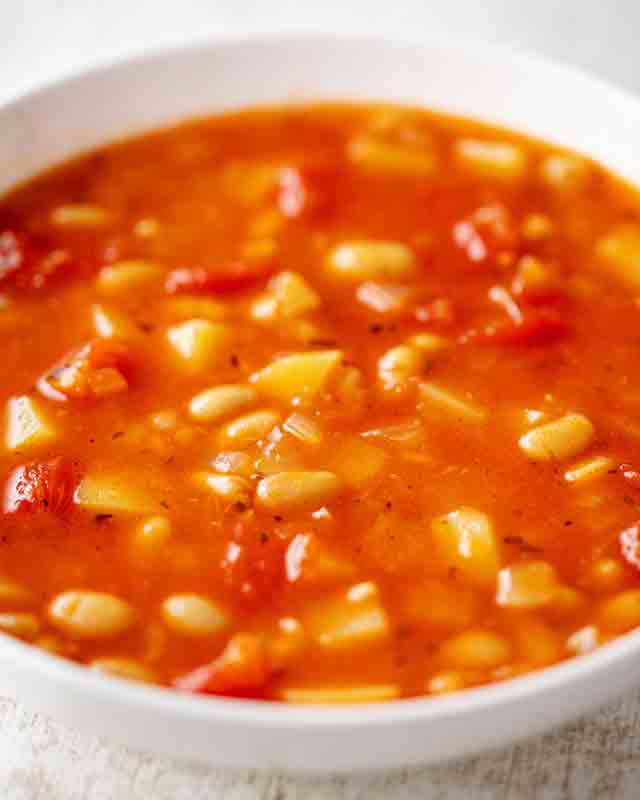 Teller mit Tomaten Kartoffel Suppe mit weißen Bohnen