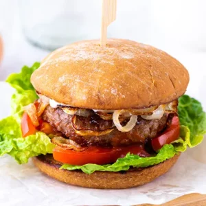 Einfacher veganer Burger mit Salat, Tomate, Burger Patty und gebratenen Zwiebelringen.