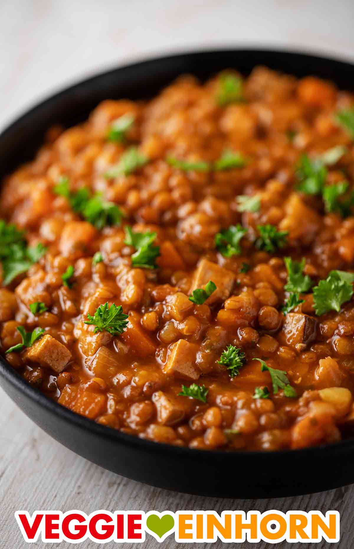 Der vegane Linseneintopf ist deftig durch den Räuchertofu. Vegane Linsensuppe mit geräuchertem Tofu auf einem Teller
