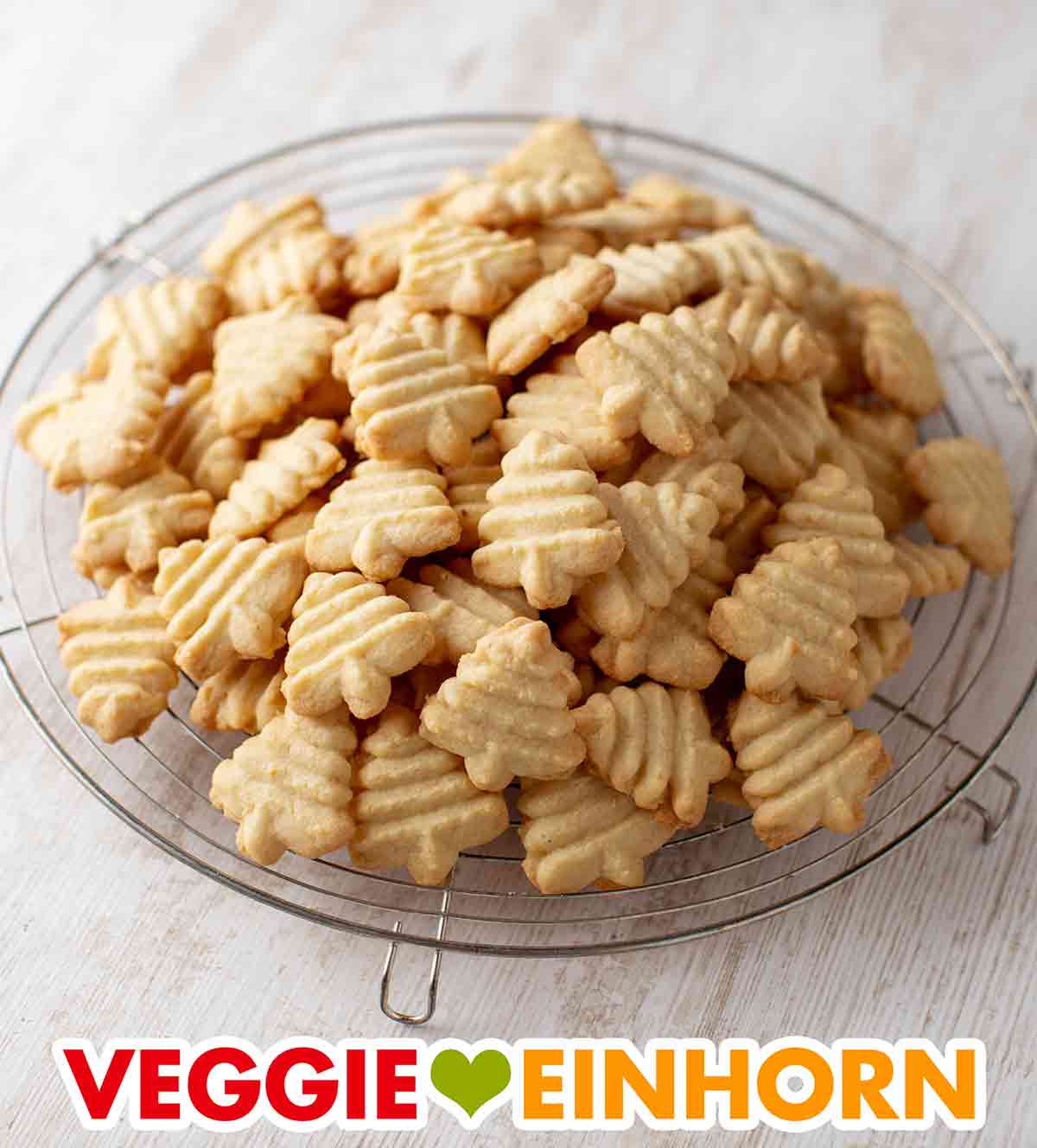 Mach am besten gleich eine große Menge. Das Spritzgebäck wird sehr schnell aufgegessen. Veganes Spritzgebäck mit Mandeln auf einem Kuchengitter