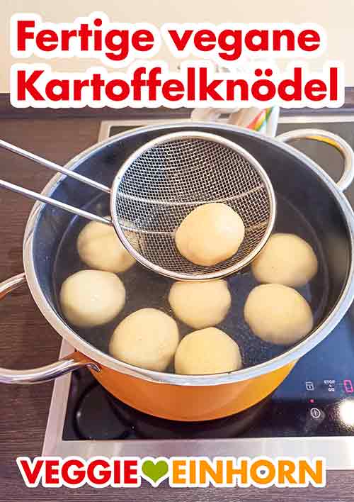 Die Kartoffelklöße mit einer Schaumkelle aus dem Wasser nehmen und sofort servieren Eine Schaumkelle mit einem fertig gekochten Kartoffelknödel