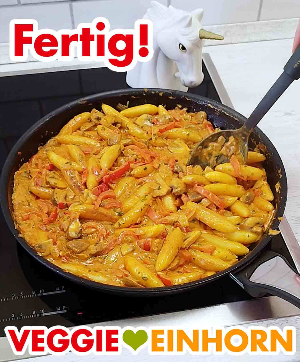 Die vegane Schupfnudelpfanne mit Paprika und Champignons ist fertig. Fertige vegane Schupfnudelpfanne mit Gemüse in der Pfanne auf dem Herd