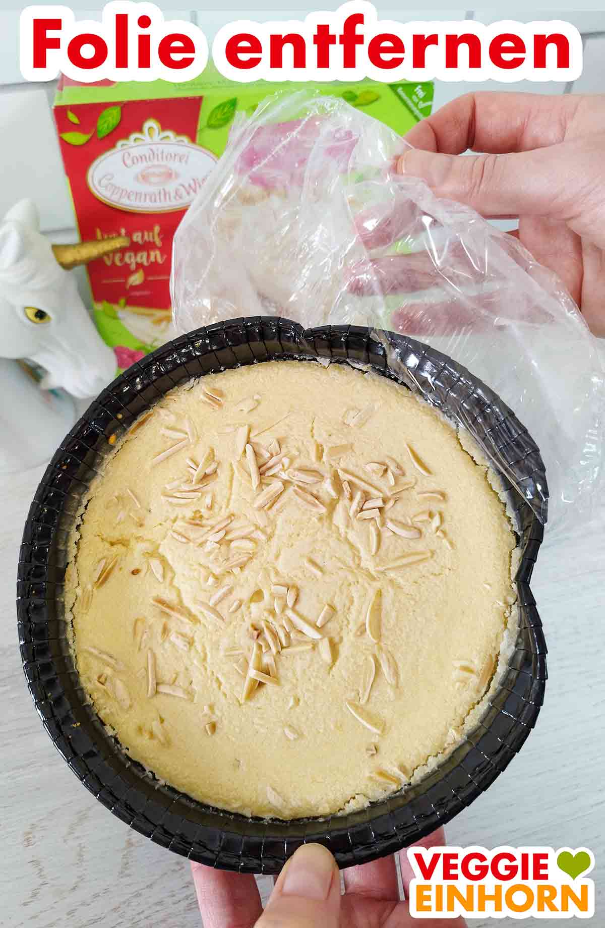 Die Folie des tiefgekühlten veganen Himbeer-Mandel-Kuchens wird entfernt. Entfernen der Folie vom veganen Himbeer Mandel Cheesecake von Coppenrath und Wiese