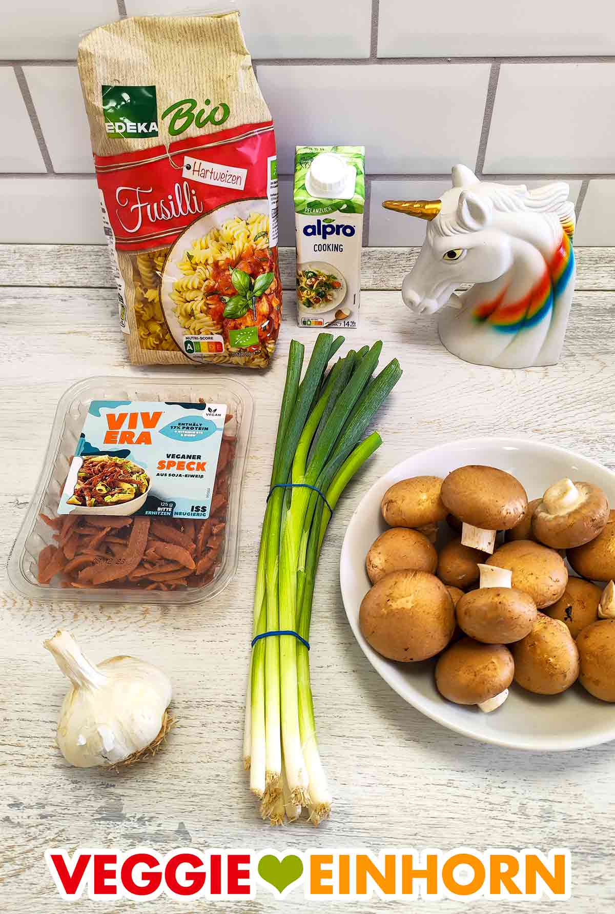 Edeka Bio Fusilli, Alpro Cooking, veganer Speck von Vivera, ein Bund Lauchzwiebeln, eine Knoblauchknolle, Pilze Nudeln, Soja Cuisine, veganer Speck, Frühlingszwiebeln, Knoblauch, braune Champignons