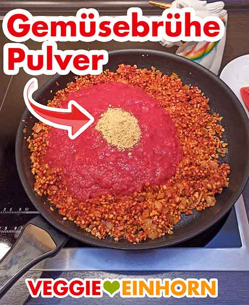Würzen mit Gemüsebrühe Pulver Gemüsebrühe Pulver und Tomatenstücke in der Pfanne
