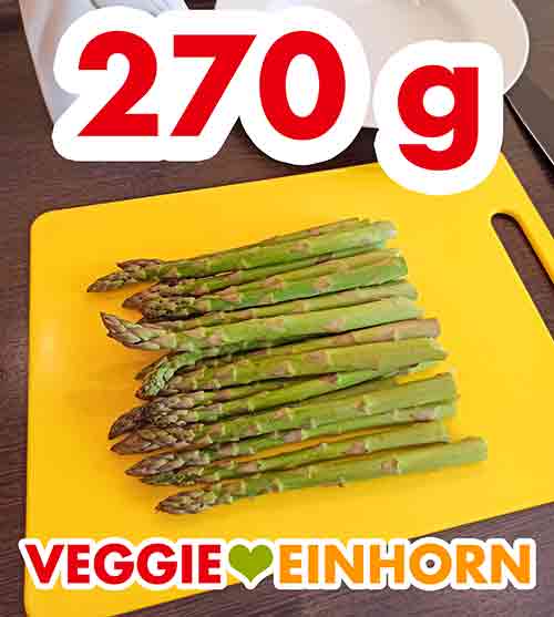Der geputzte grüne Spargel 270 g Spargel auf einem Schneidebrett.