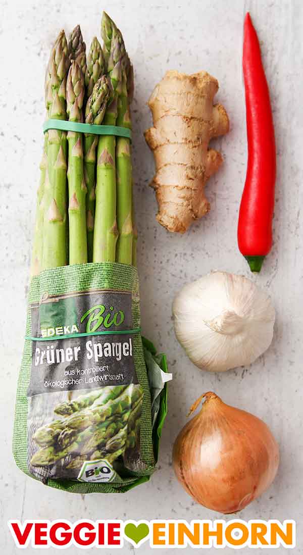 Ein Bund grüner Spargel von Edeka Bio, Ingwr, Chili, Knoblauch und Zwiebel Grüner Spargel, frischer Ingwer, eine rote Chili Schote, eine Knolle Knoblauch und eine kleine Zwiebel.