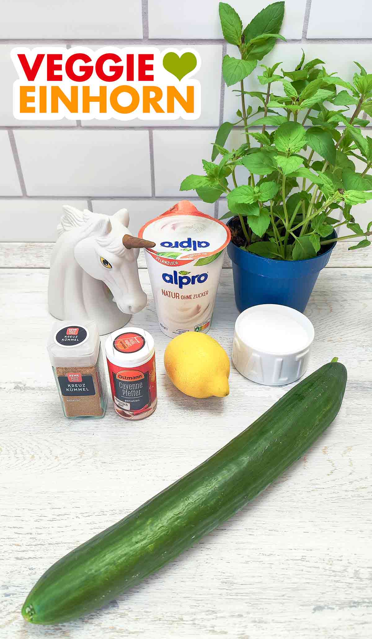 alpro Natur ohne Zucker, ein Topf mit frischer Minze, Rewe Beste Wahl gemahlener Kreuzkümmel, Ostmann Cayenne Pfeffer, Zitrone, Salz, Gurke Sojajoghurt ohne Zucker, frische Minze, Kumin, Cayennepfeffer, Zitrone, Salz, Salatgurke