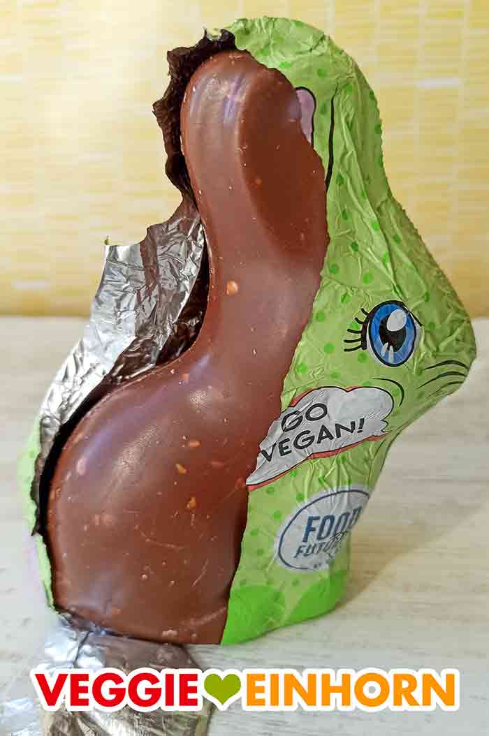 Der vegane Schokohase wird ausgepackt. Die Folie des veganen Schoko Osterhasen ist halb abgezogen