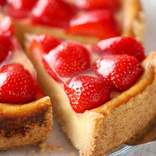 Ein Stück veganer Käsekuchen mit Erdbeeren auf einem Tortenheber