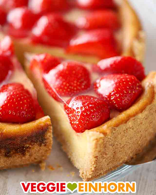 Ein Stück veganer Käsekuchen mit Erdbeeren auf einem Tortenheber