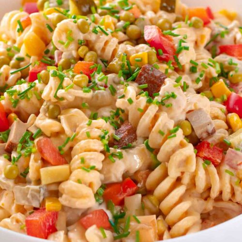 Klassischer veganer Nudelsalat mit Räuchertofu, Mayonnaise, Erbsen, Paprika, Mais und Essiggurken in einer Salatschale, von oben gesehen