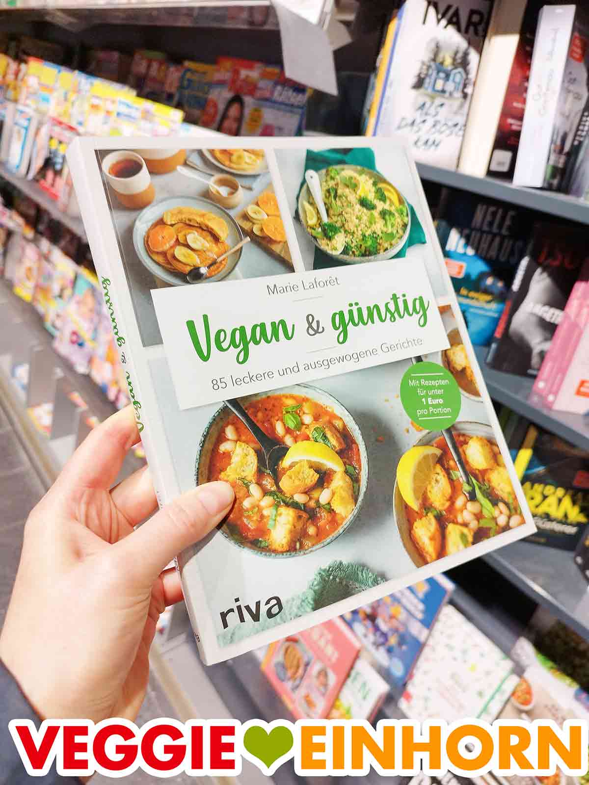 Das vegane Kochbuch Vegan und Günstig von Marie Laforêt bei Combi. Eine Hand hält das Buch Vegan und Günstig in der Buchabteilung im Supermarkt