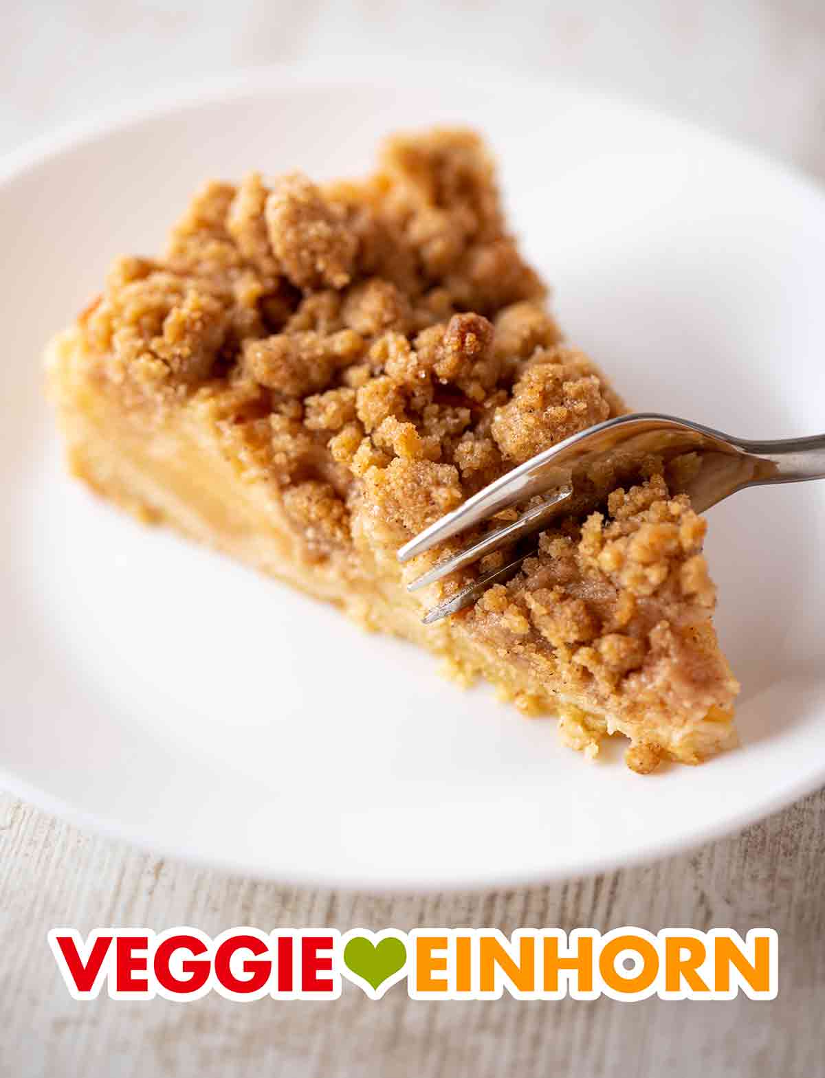 Der vegane Streuselkuchen mit Äpfeln und Zimt ist lecker und saftig. Kuchengabel mit einem Stück veganen Apfelkuchen mit Zimtstreuseln