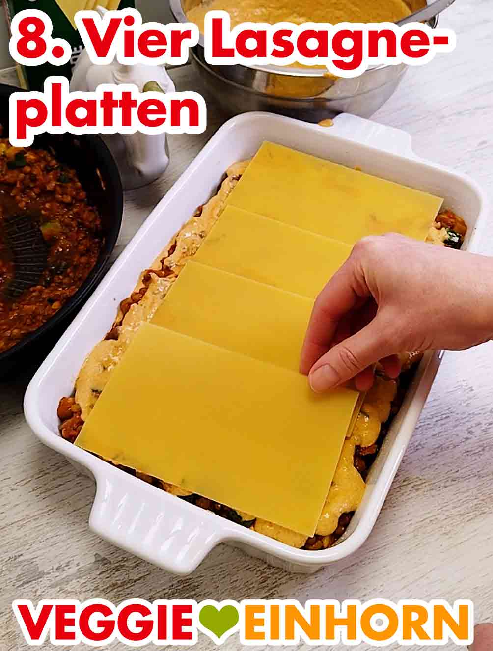 Für die vegane Linsenlasagne mit Zucchini brauchst Du insgesamt 12 Lasagneblätter. Eine Hand legt eine Lasagneplatte in eine Auflaufform
