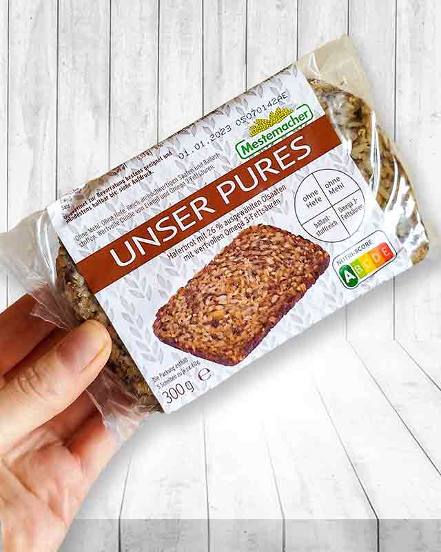 Eine Hand hält eine Packung Mestemacher Unser Pures