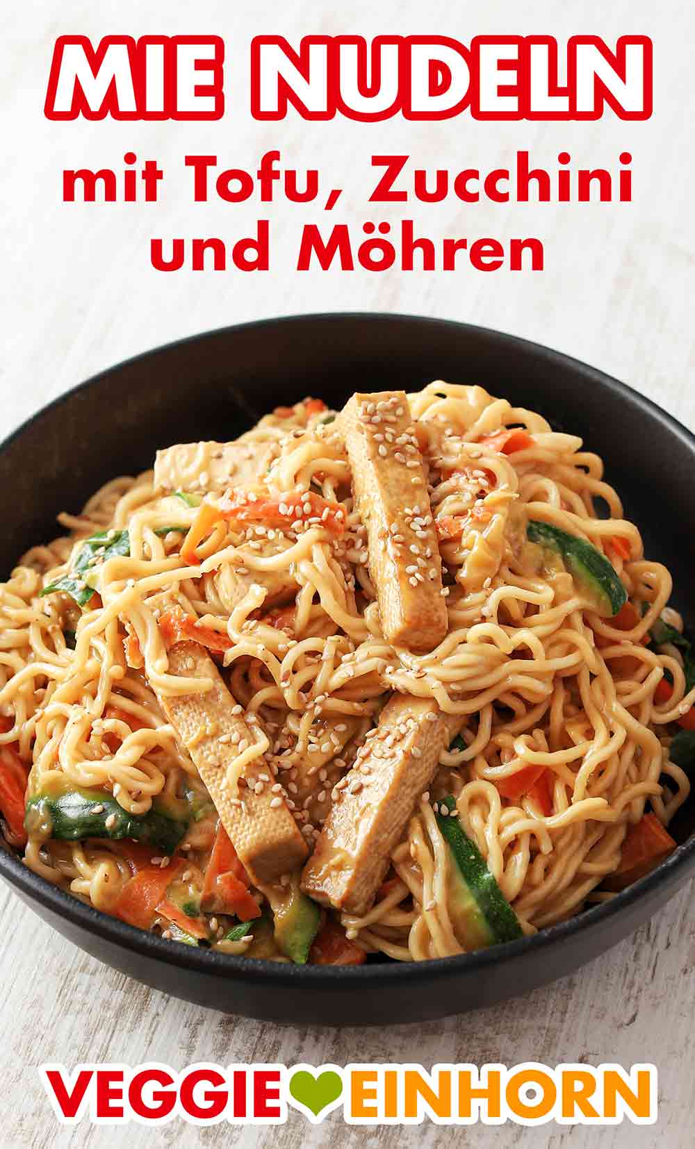 Das vegane Rezept mit Mie Nudeln und Tofu ist einfach und schnell. Mie Nudeln mit Tofu, Zucchini, Möhren und Sesam auf einem Teller