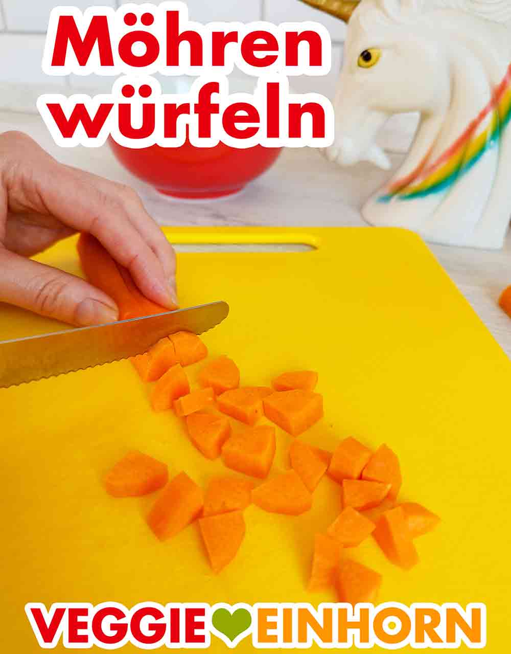 Würfeln der Möhren Eine Karotte wird auf einem Schneidebrett mit einem Messer in kleine Stücke geschnitten