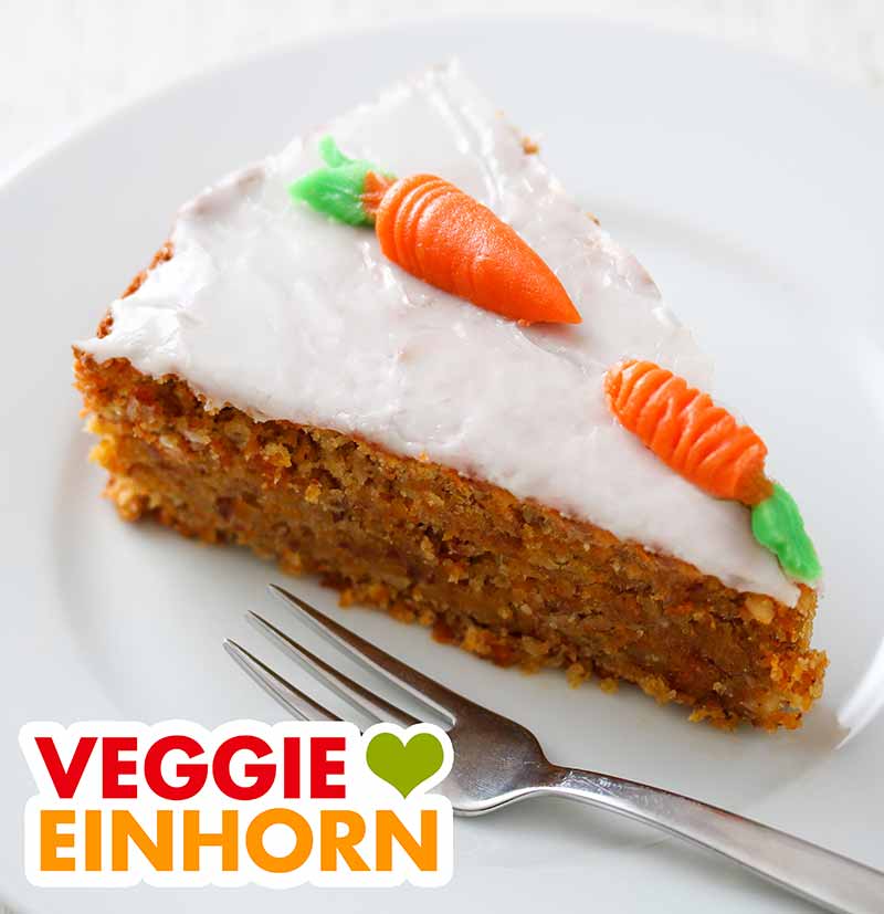 Möhrenkuchen dekoriert mit Marzipanmöhren Ein Stück Möhrenkuchen mit zwei Marzipanmöhren