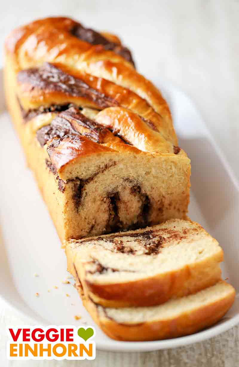 Angeschnittener veganer Nutella Babka Babka mit veganer Nuss-Nougat-Creme auf einer Kuchenplatte
