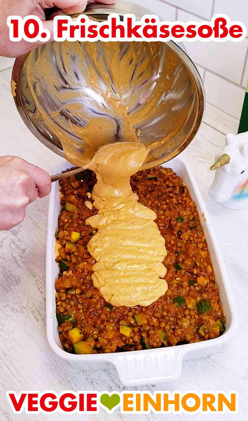 Jetzt kommt die ganze restliche Frischkäsesoße. Vegane Frischkäse-Pesto-Sauce wird aus der Schüssel oben auf die Lasagne gegeben.