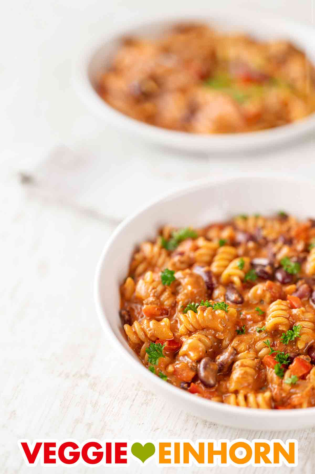 Die vegane One Pot Pasta ist ein beliebtes Nudelgericht mit veganem Hack. Zwei Teller mit veganer One Pot Pasta mit veganem Hackfleisch und Kidneybohnen