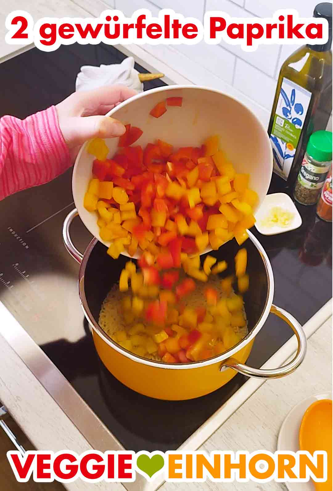 Eine rote und eine gelbe gewürfelte Paprika zufügen. Zwei gewürfelte Paprika werden in den Topf zu dem Reis gegeben.