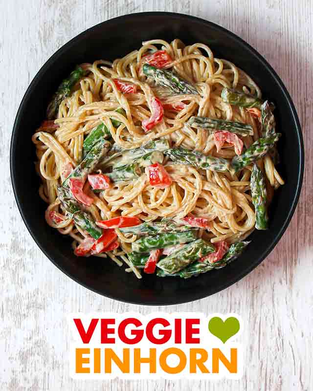 Ein Teller Pasta mit gebratenem grünen Spargel und roter Paprika