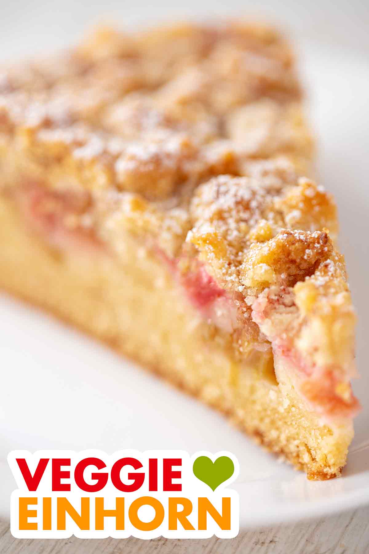 Saftiger veganer Streuselkuchen mit Rhabarber Ein Stück veganer Rhabarber Streuselkuchen auf einem Kuchenteller