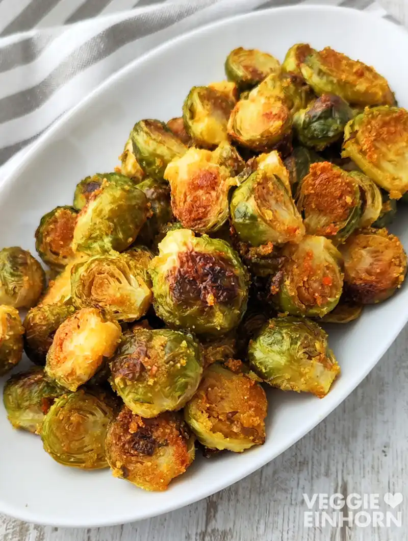 Ofengerösteter Rosenkohl mit goldbrauner Kruste auf einer weißen Servierplatte.