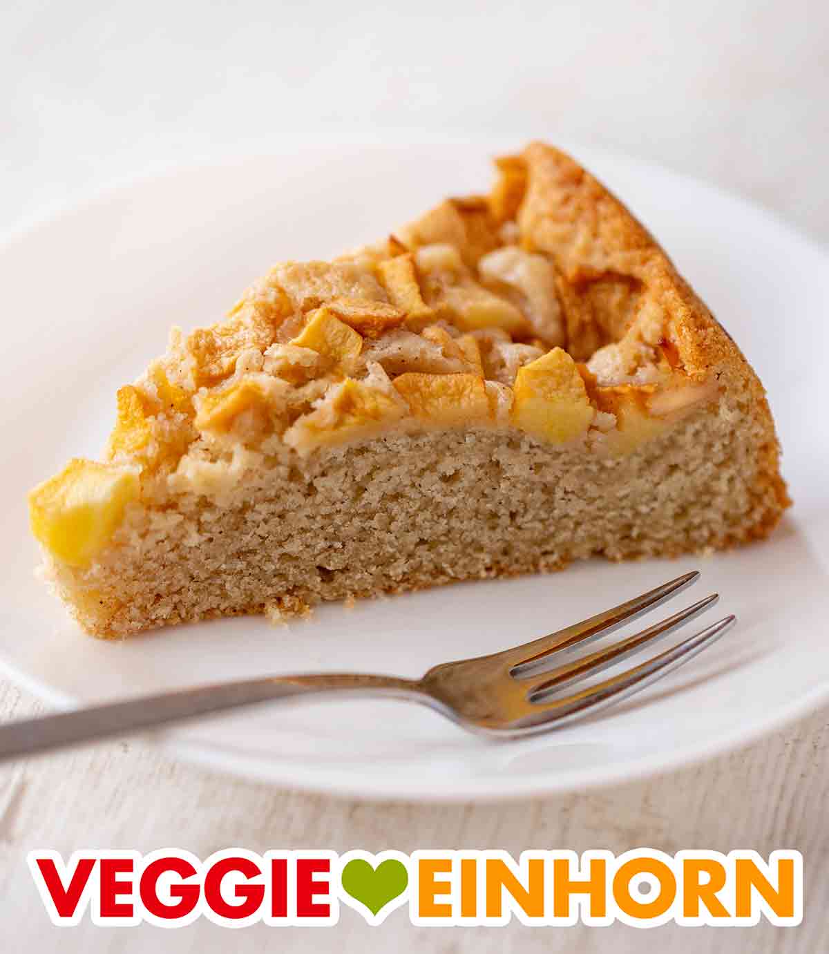 Der Kuchen ist total saftig und lecker. Ein Stück Apfelkuchen mit veganer Butter auf einem Kuchenteller