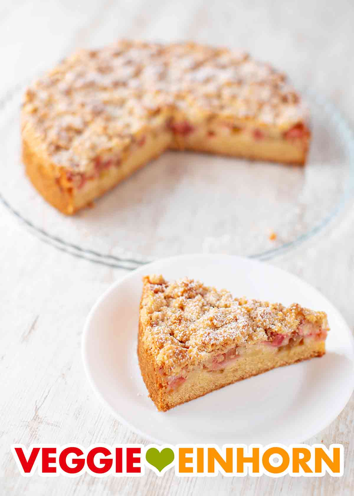 Der vegane Streuselkuchen mit Rhabarber ist sehr lecker und kommt immer gut an. Veganer Rhabarber Streuselkuchen auf der Kuchenplatte und ein Stück auf einem Kuchenteller