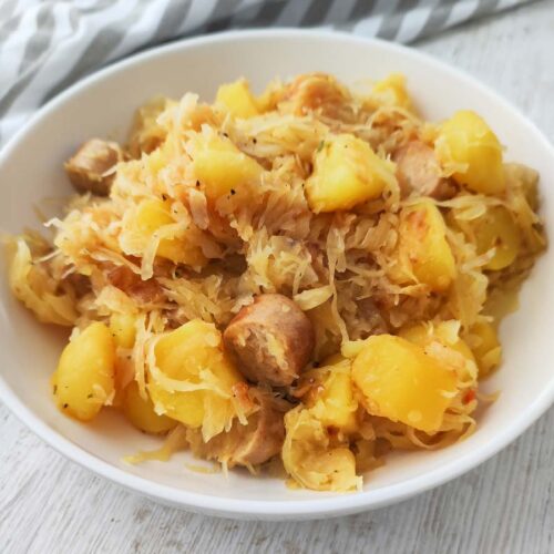 Teller mit veganer Kartoffel Bratwurst Pfanne mit Sauerkraut.