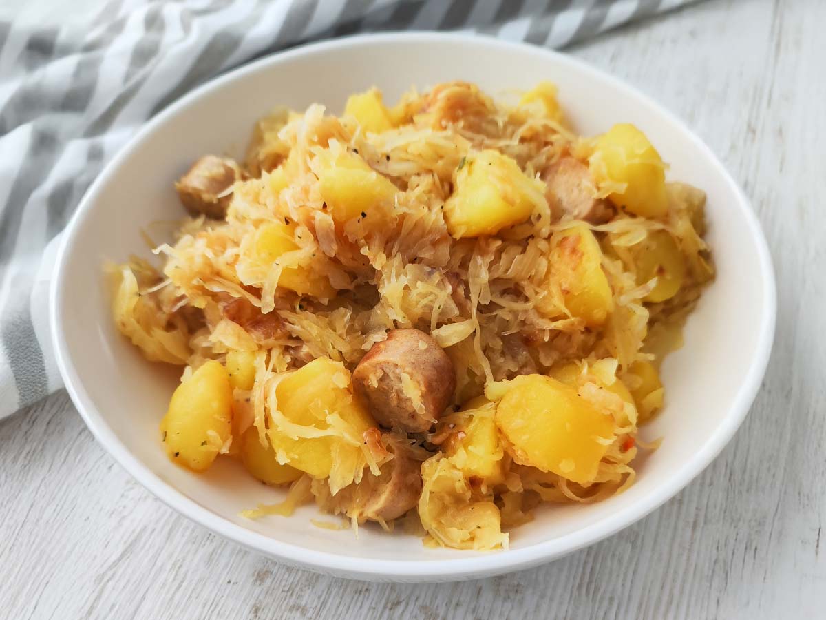 Teller mit veganer Kartoffel Bratwurst Pfanne mit Sauerkraut.