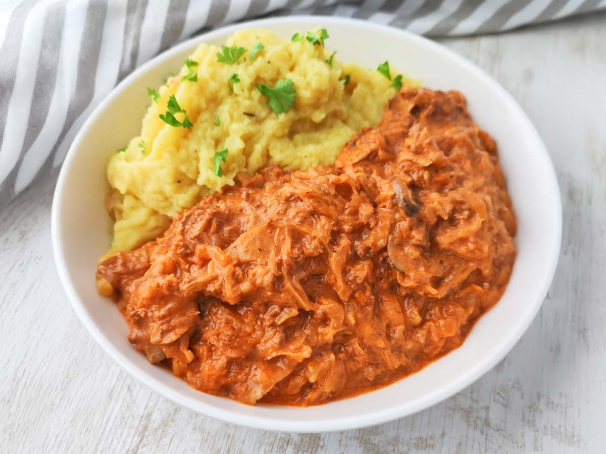 Ein Teller mit veganer Sauerkrautpfanne und Kartoffelpüree.