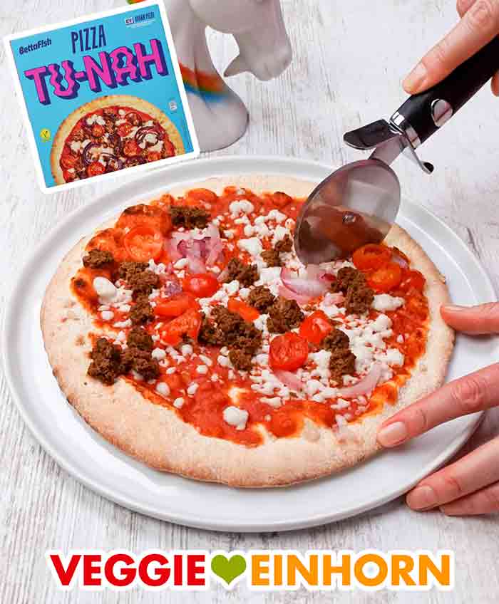 Schneiden der veganen Pizza Tu-Nah Die vegane Thunfisch Fertigpizza wird mit einem Pizzaroller geschnitten.