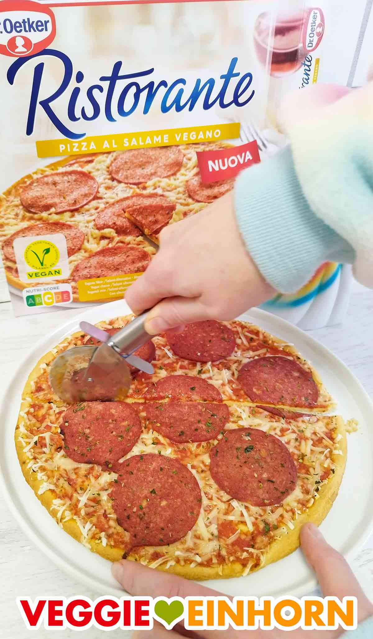 Ich schneide die Dr. Oetker Pizza al Salame Vegano mit einem Pizzaschneider in Stücke. Schneiden der veganen Salami Pizza Ristorante mit einem Pizzaroller