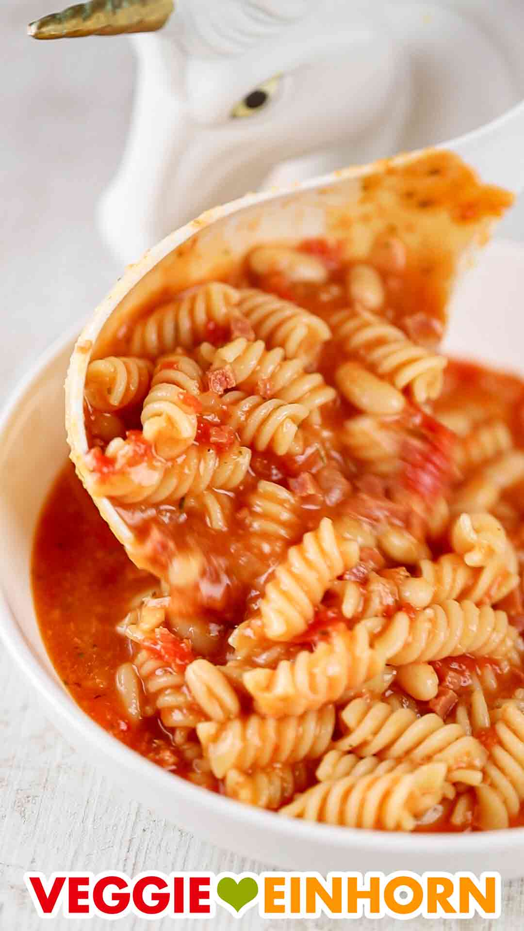 Die italienische Nudelsuppe mit weißen Dosenbohnen und veganem Speck wird aufgefüllt. Schöpfkelle mit italienischer weißer Bohnensuppe mit veganem Speck und Nudeln
