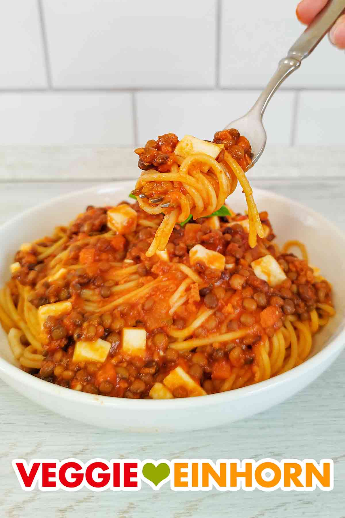 Spaghetti mit Linsen und veganem Feta auf einer Gabel
