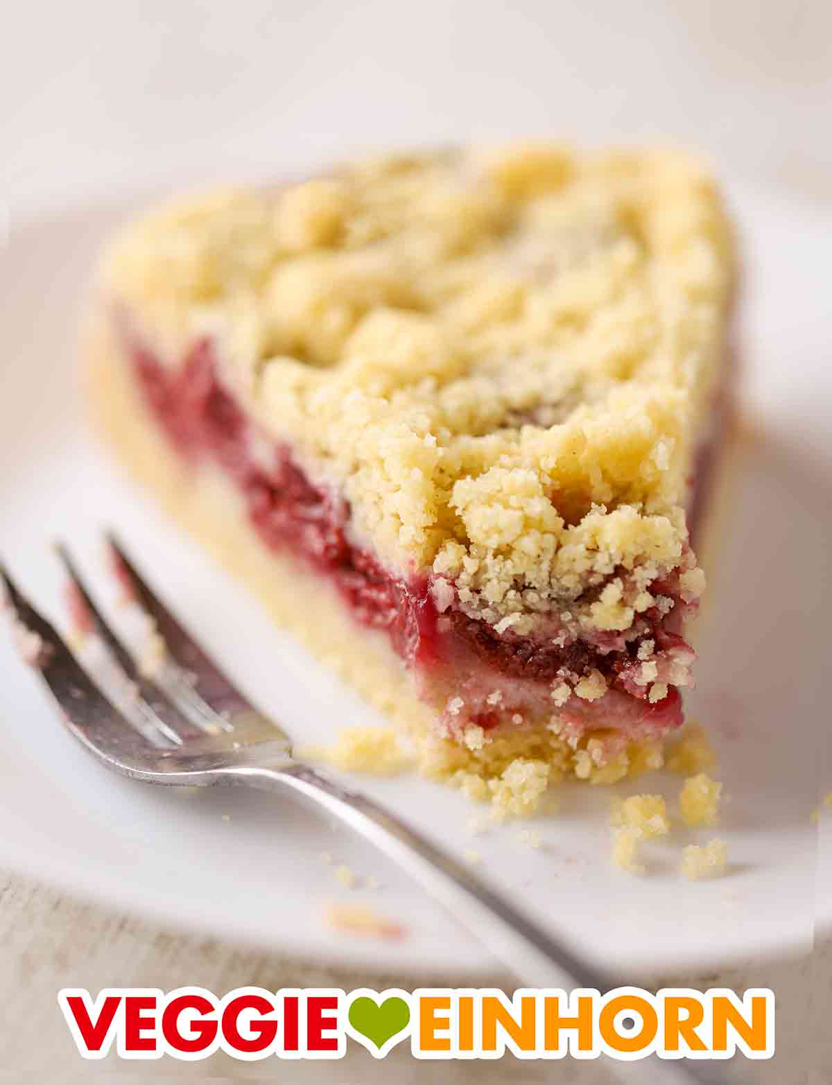 Der Kirschkuchen mit Streuseln ist einfach und saftig. Ein Stück Kirsch Streuselkuchen mit einer Kuchengabel auf einem Teller