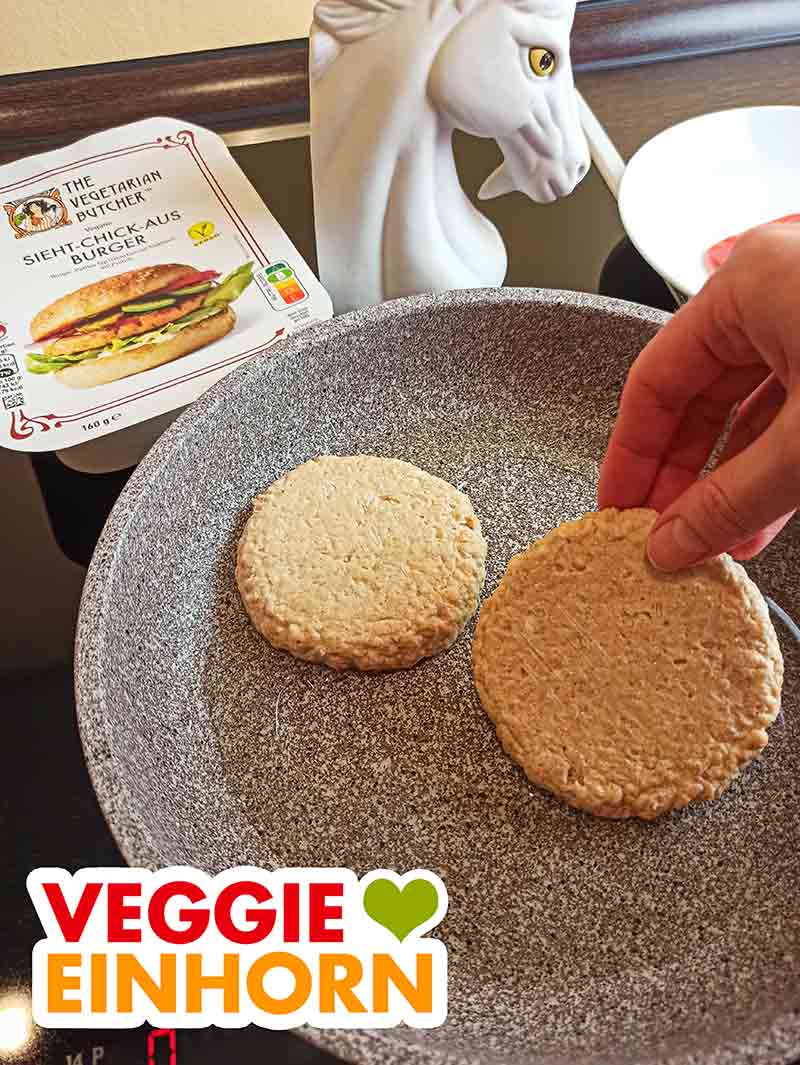 Ich habe die veganen Sieht-Chick-Aus Burger in der Pfanne zubereitet. Zwei vegane Chicken Burger werden in eine Bratpfanne gelegt