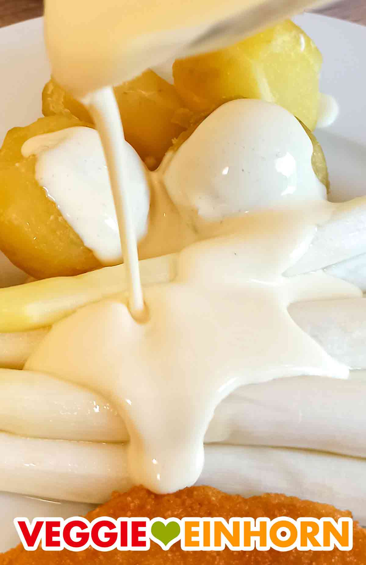 Die vegane Sauce Hollandaise von bedda passt fantastisch zu Spargel. Nahaufnahme der veganen Sauce Hollandaise von bedda auf weißem Spargel